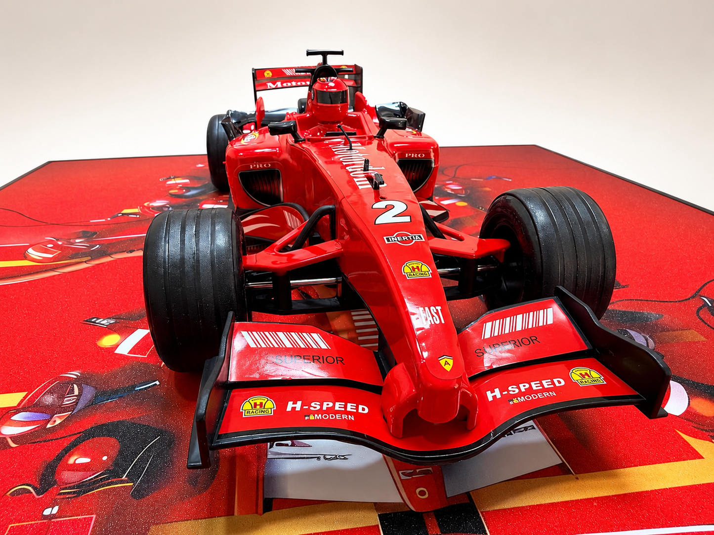 A red Ferrari F1 race car model displayed on a red printed stand against a plain light background.