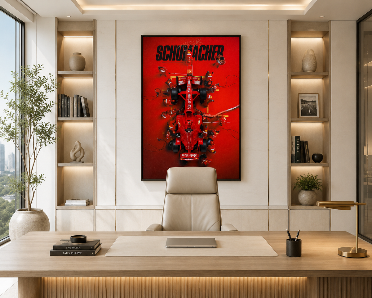 A framed red Schumacher wall art print hangs above a light wood desk in a modern office setting with built-in shelves, a beige chair, and a plant.
